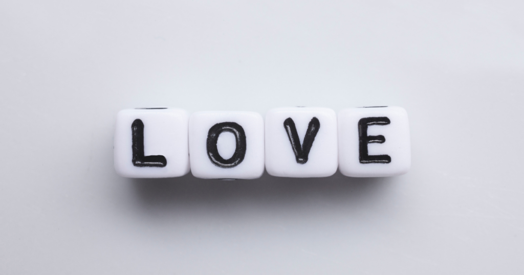 White cube beads spelling 'LOVE' on a light gray surface.