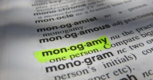 Close-up of a dictionary page with the term 'mon-og-amy' highlighted in neon green/yellow.