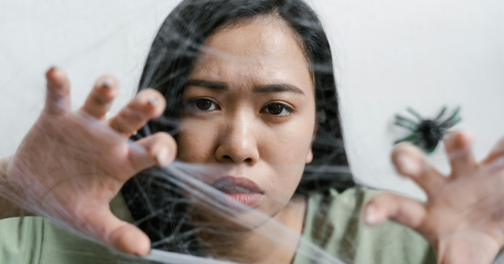 adhd-paralysis-breaking-free-guide-image-2 - Shine Mental Health Woman peers through a clear plastic wrap barrier, hands pressed against it, with a tense expression.